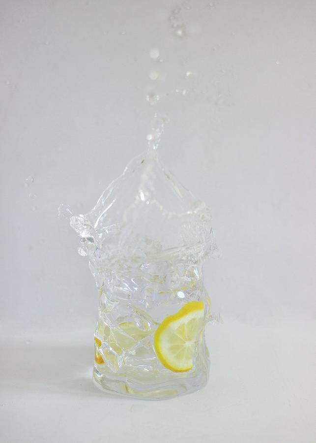 Gin And Tonic Splashing Out Of A Glass Against A White Background Photograph by Vernica Orti