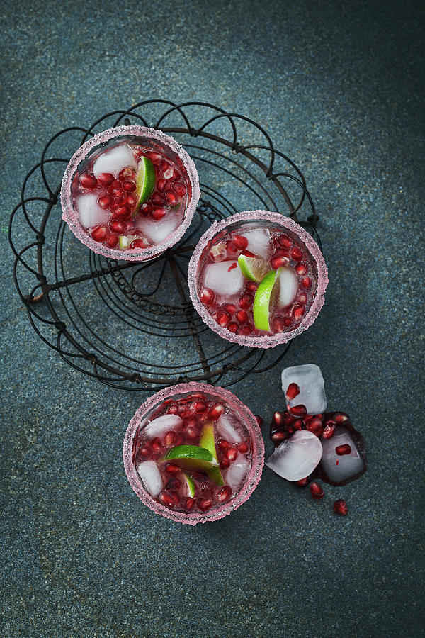 Gin And Tonic With Pomegranate Seeds In Glasses With Sugared Rims, Ice And Limes Photograph by Stefan Schulte-ladbeck