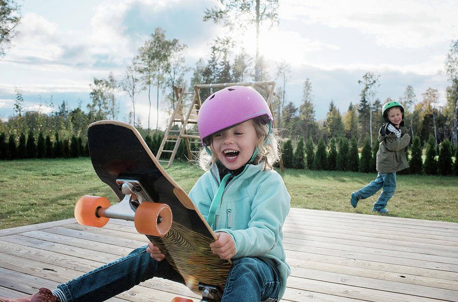 Girl Sat On A Skateboard Laughing With Her Brother Playing At Home ...