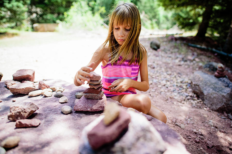 Girl Photograph - Girl Stacking Stones While Crouching In Forest by Cavan Images