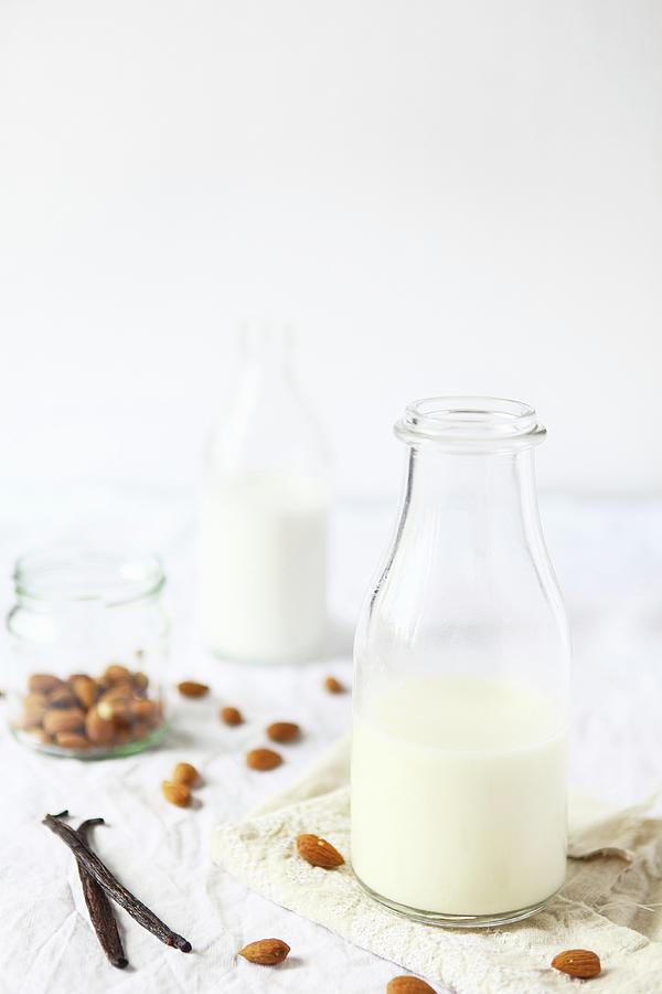 Glass Bottles Of Almond Milk, Almonds And Vanilla Pods Photograph by Sabrina Sue Daniels