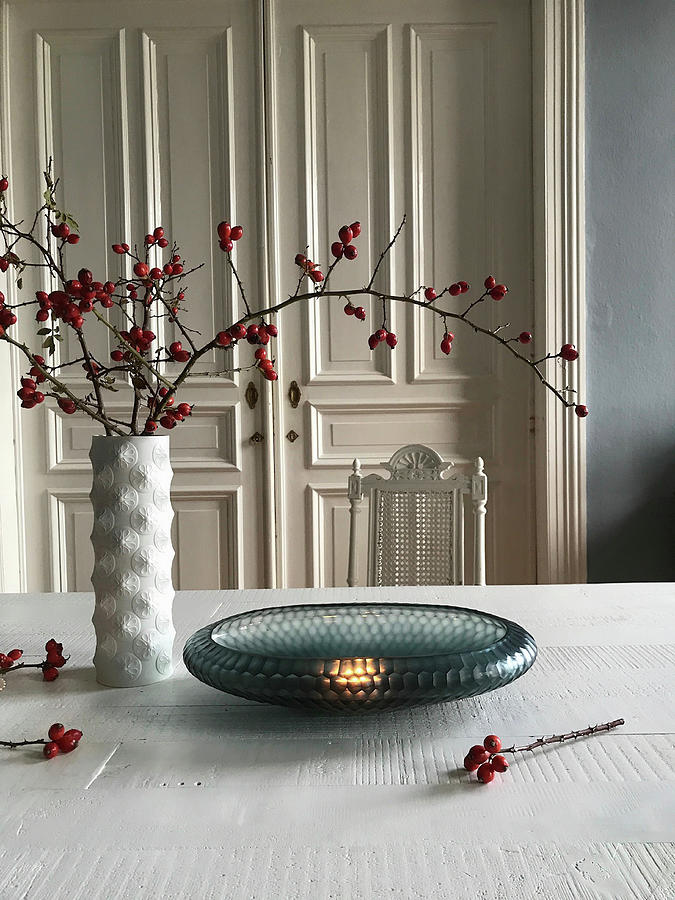Glass Bowl And Branches Of Rose Hips On Table In Front Of Antique Wooden Door Photograph by Mimameise