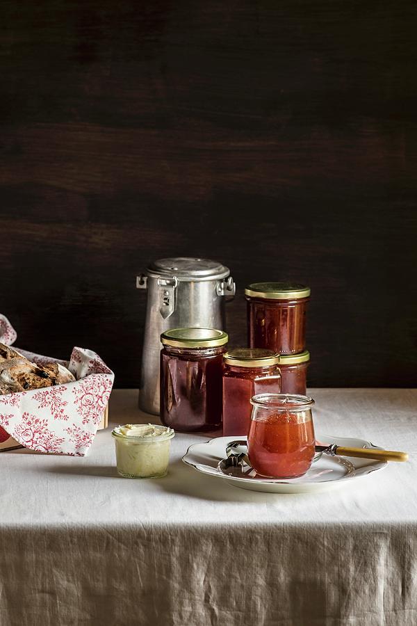 Glass Jars With Amber Colored Jam, Butter Jar And Milk Can On White Table Photograph by Miriam Garcia