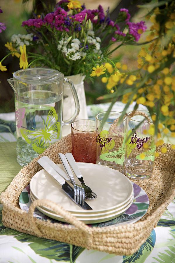 Glasses, Jug Of Water And Plates On Basket Tray Outdoors Photograph by Winfried Heinze