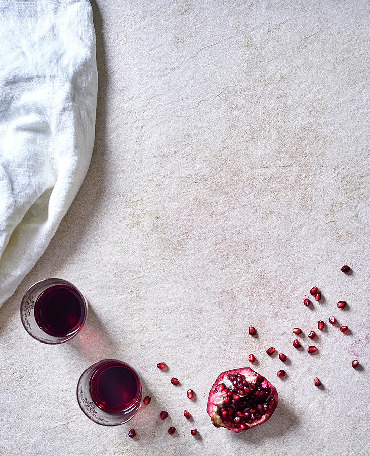 Glasses Of Red Wine And Pomegranate Wedges With Seeds On A White Surface Photograph by Great Stock!