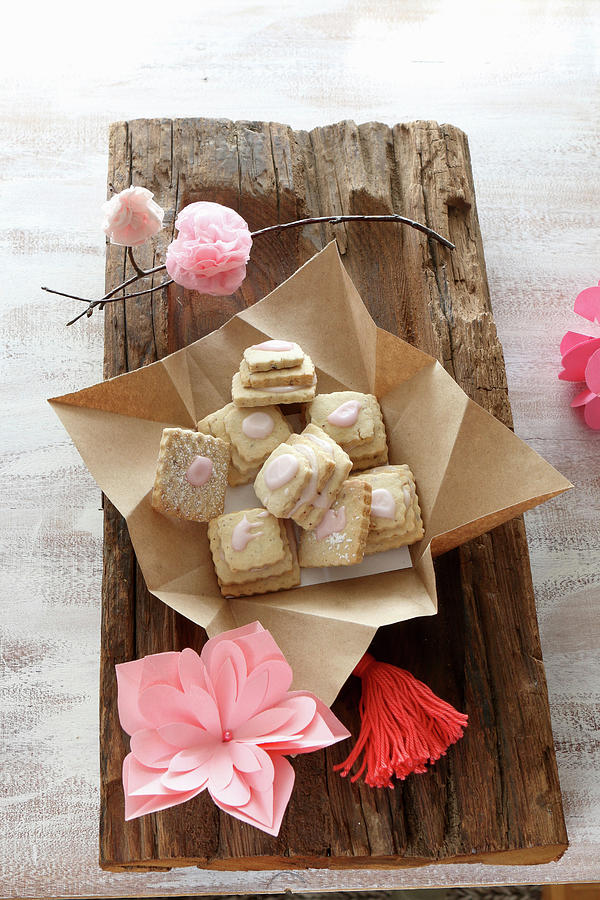 Gluten-free Layered Biscuits With Pink Icing And Pink Paper Flowers On A Rustic Wooden Board Photograph by Regina Hippel