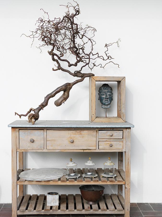 Gnarled Branch And Head Of Buddha In Wooden Frame On Top Of Simple Wooden Sideboard With Drawers And Shelves Photograph by Peter Carlsson