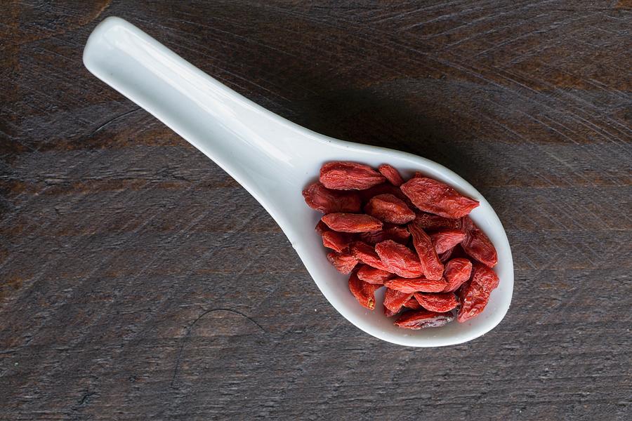 Goji Berries On A Porcelain Spoon On A Dark Surface Photograph by Nicole Godt
