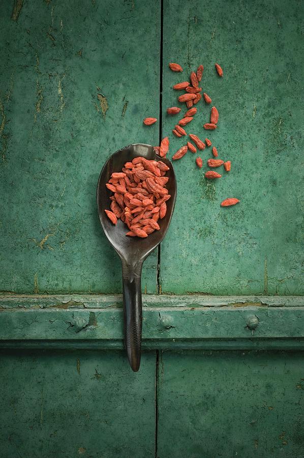 Goji Berries On A Spoon On A Rustic Surface Photograph by Achim Sass