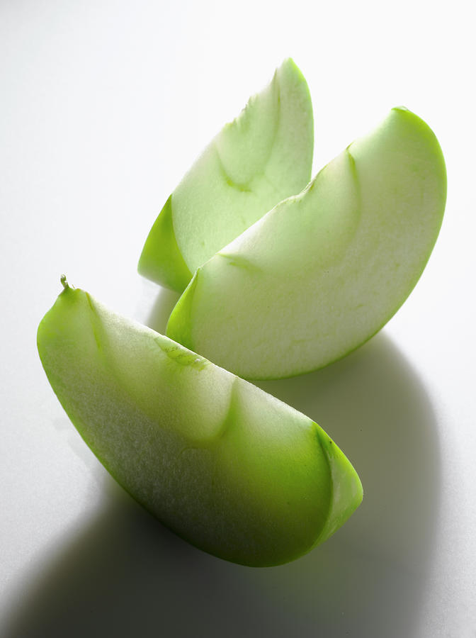 Granny Smith Apple Pieces On White Photograph by Howard Bjornson