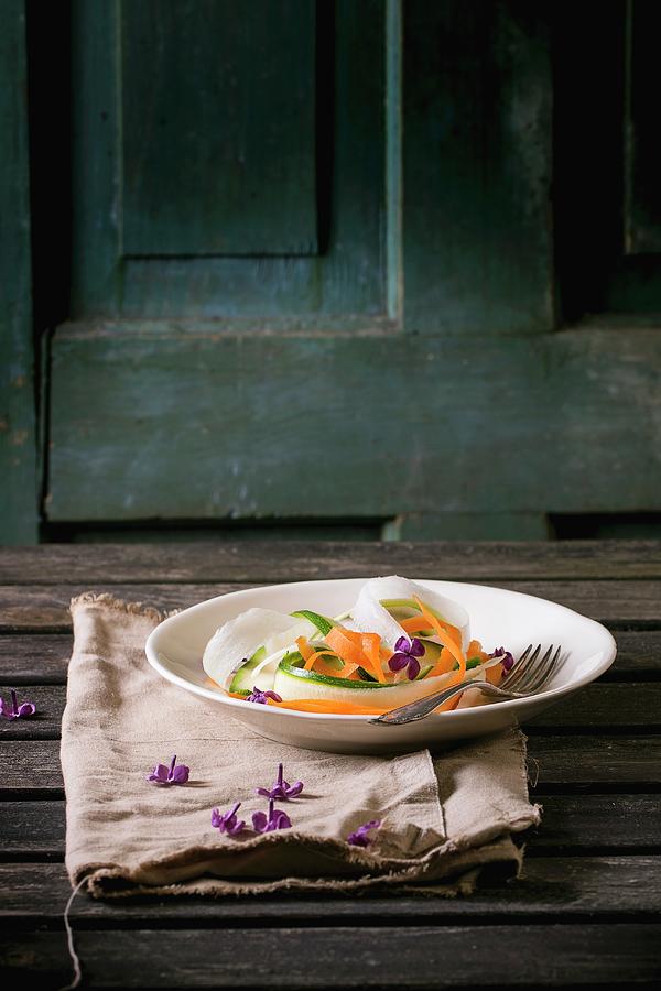 Grated Vegetable Tagliatelle Made Of Carrots, Radish And Courgette On A Plate With Lilac Flowers Photograph by Natasha Breen