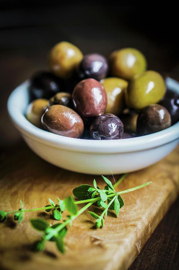 Green And Black Olives In A Dish On A Chopping Board Photograph by Alena Haurylik