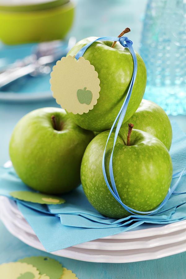Green Apples With Satin Ribbon And Tag On Stacked Plates Photograph by Franziska Taube