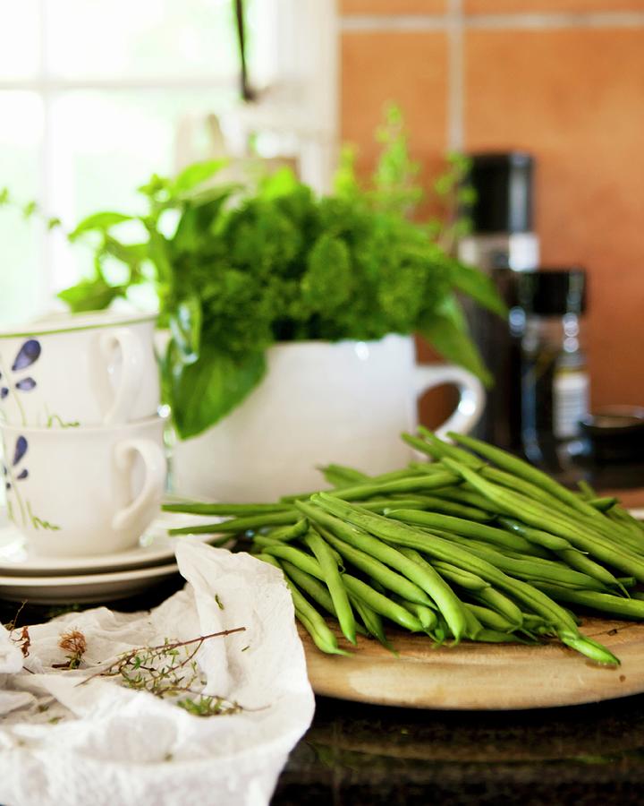 Green Beans On A Wooden Plate In Front Of Porcelain Crockery With A Herb Bouquet Photograph by Great Stock!