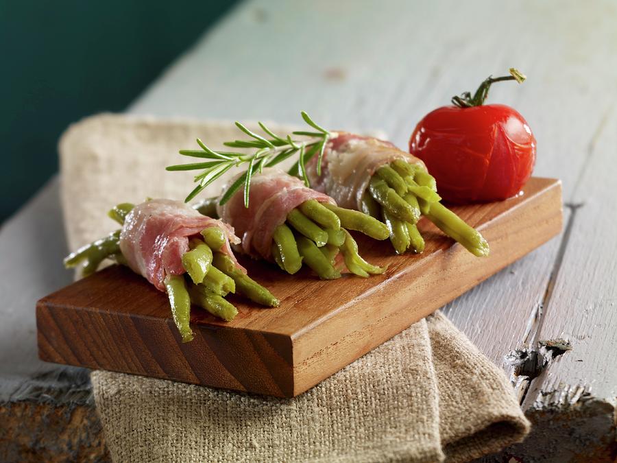 Green Beans Wrapped In Bacon With Rosemary On A Small Wooden Board Photograph by Studio R. Schmitz