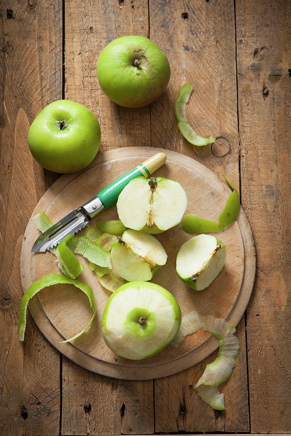 Green Bramley Apples, Whole And Peeled, With An Apple Peeler Photograph by Stacy Grant