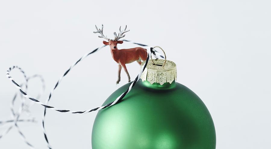 Green Christmas Bauble Decorated With Miniature Reindeer Figurine Photograph by Andreas Hoernisch