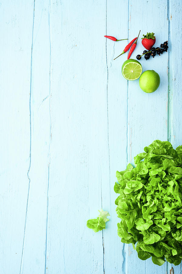Green Lettuce And Fruits On A Light Blue Wooden Surface Photograph by Stockfood Studios / Andrea Thode Photography