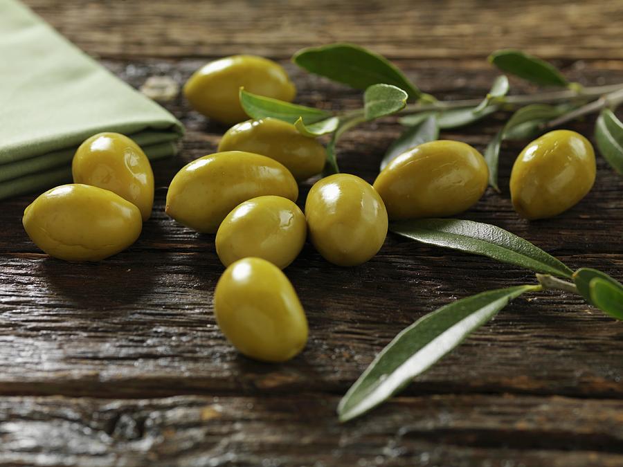 Green Olives With Leaves On A Wooden Surface Photograph by Robert Morris
