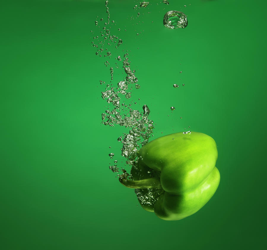 Green Pebber Fruit Splashed Into Water Photograph by Henrik Sorensen