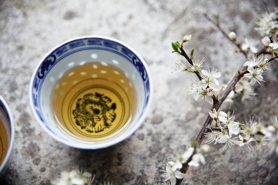 Green Tea In An Oriental Tea Bowl Next To A Sprig Of Cherry Blossom Photograph by George Blomfield
