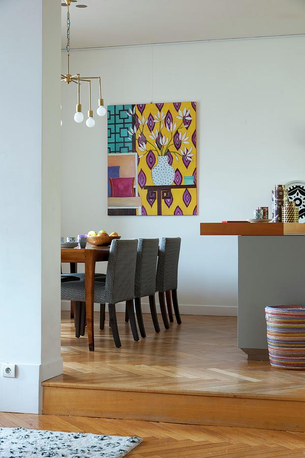 Grey-covered Chairs Around Table Below Art-deco Pendant Lamp In Dining Room With Modern Artwork On Wall Photograph by Christophe Madamour