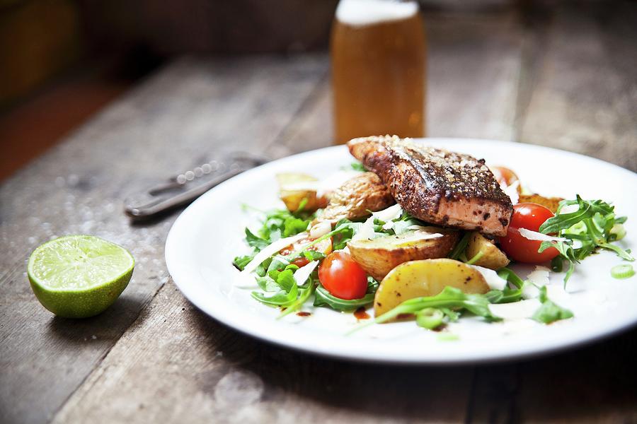 Grilled Cajun Salmon Steak On A Bed Of Potato Wedges And Rocket And Tomato Salad With Parmesan Photograph by George Blomfield