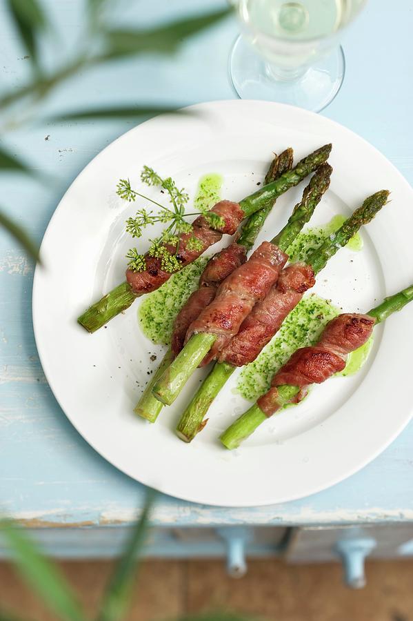 Grilled Green Asparagus Wrapped In Bacon With A Herb Sauce Photograph by Gerlach, Hans