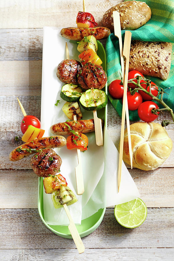 Grilled Skewers With Meatballs, Sausages And Vegetables From New Zealand With Cherry Tomatoes And Bread Rolls Photograph by Teubner Foodfoto