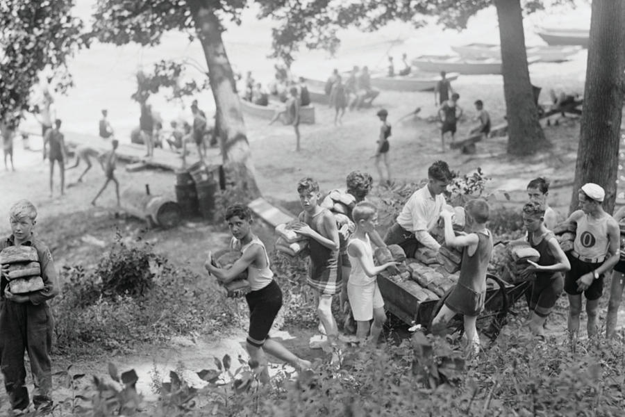 Group of Boys carry loaves of bread from wagons near beach front in woods. Painting by 