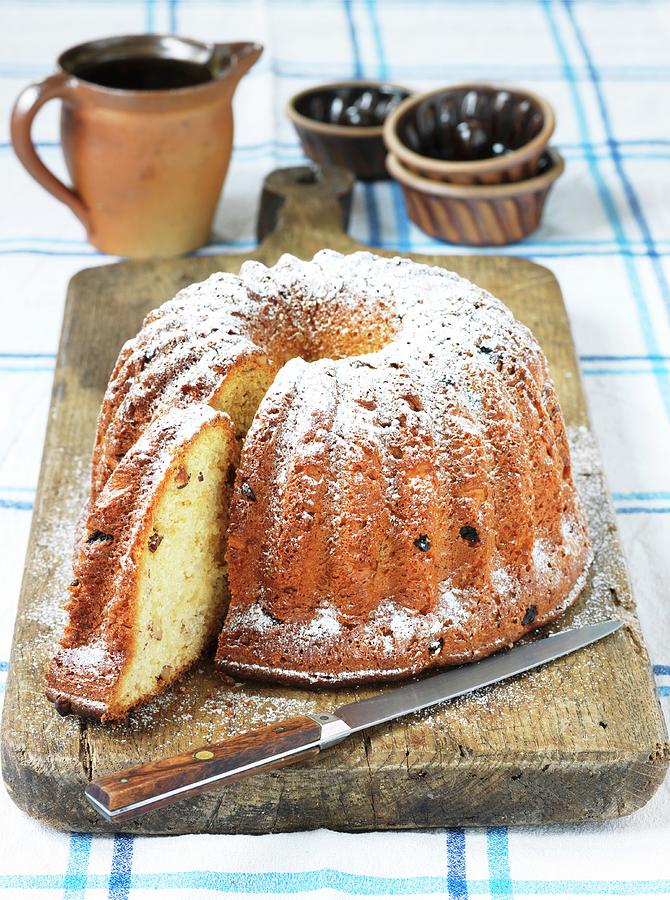 Gugelhupf With Raisins And Icing Sugar, Partly Sliced Photograph by Nicolas Leser