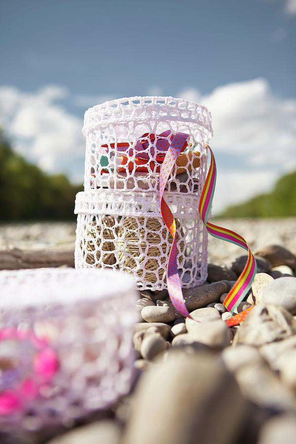 Haberdashery Supplies In Two, Stacked, White Crocheted Containers On Pebbly River Bank Photograph by Nikky Maier