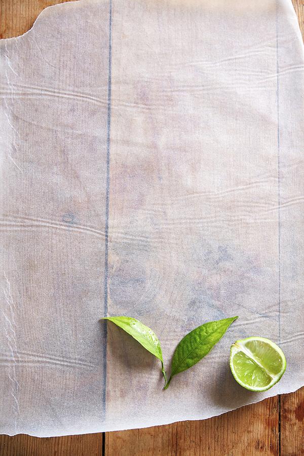 Half A Lime With Leaves On A Piece Of Paper Photograph by Great Stock!