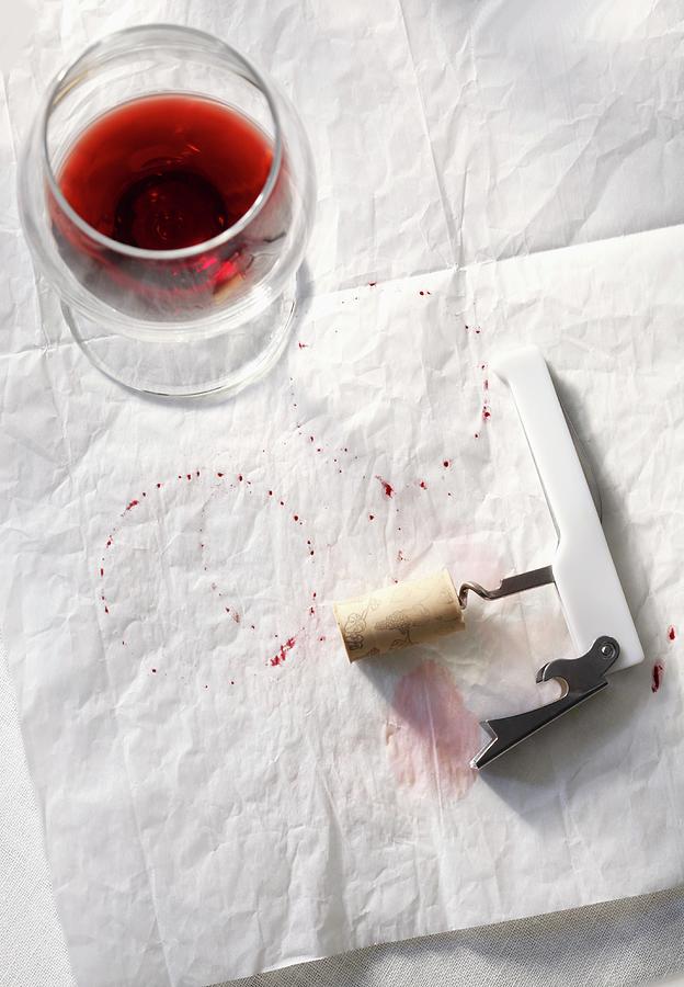 Half Empty Glass Of Red Wine With Corkscrew And Wine Stains On Paper Photograph by Pollak, Katharine
