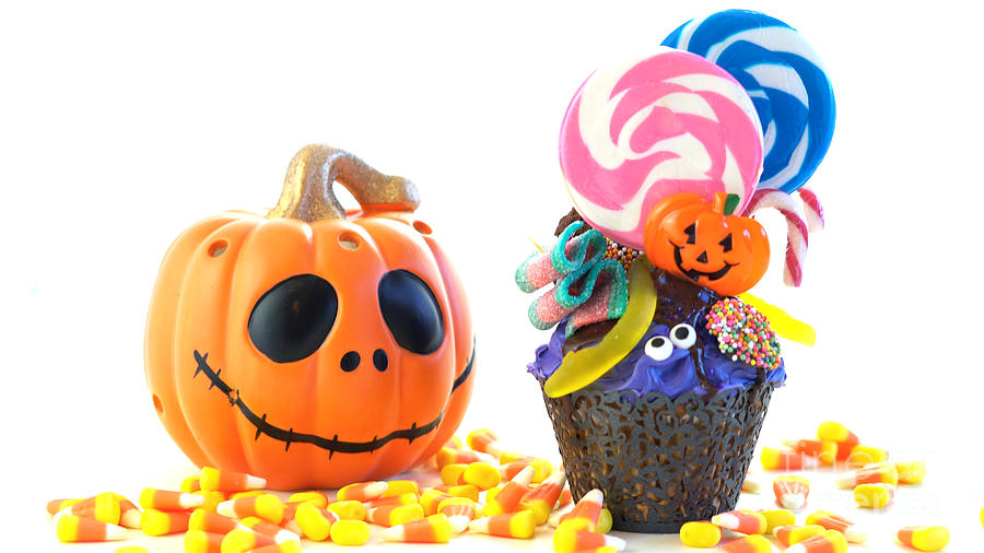 Halloween candyland drip cake style cupcakes with lollipops and candy on white. Photograph by Milleflore Images
