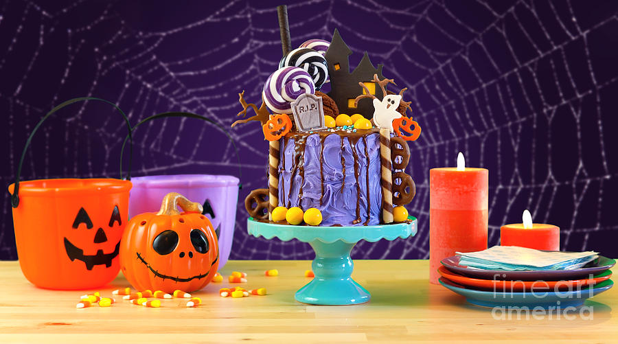 Halloween candyland novelty drip cake in colorful purple party setting. Photograph by Milleflore Images
