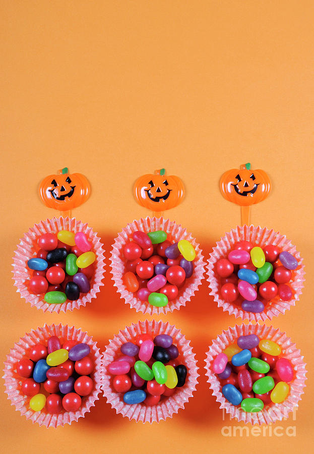 Halloween trick or treat candy on orange background. Photograph by Milleflore Images