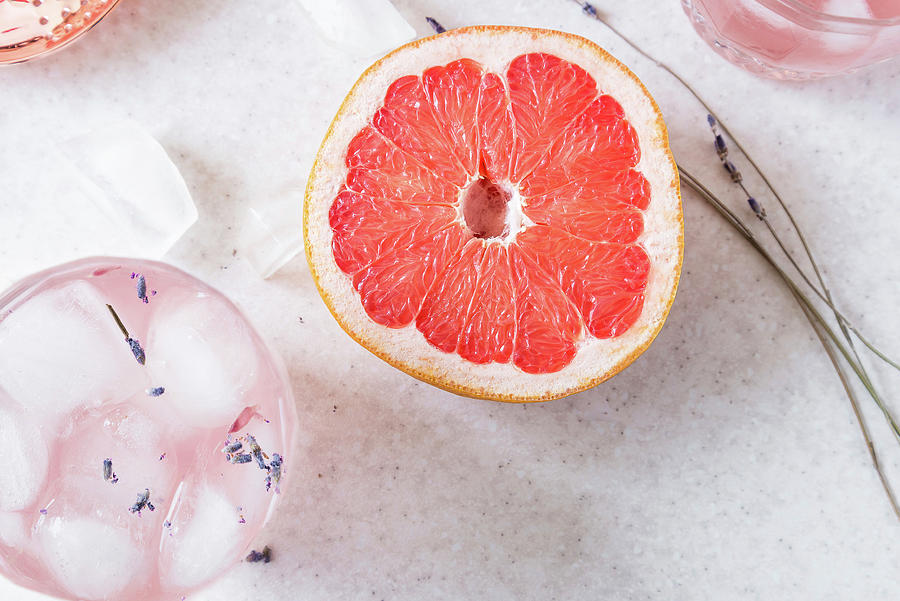 Halved Grapefruit, Dry Lavender, And Glasses Of Grapefruit, Gin And Lavender Fizz With Ice Cubes Photograph by Albina Bougartchev
