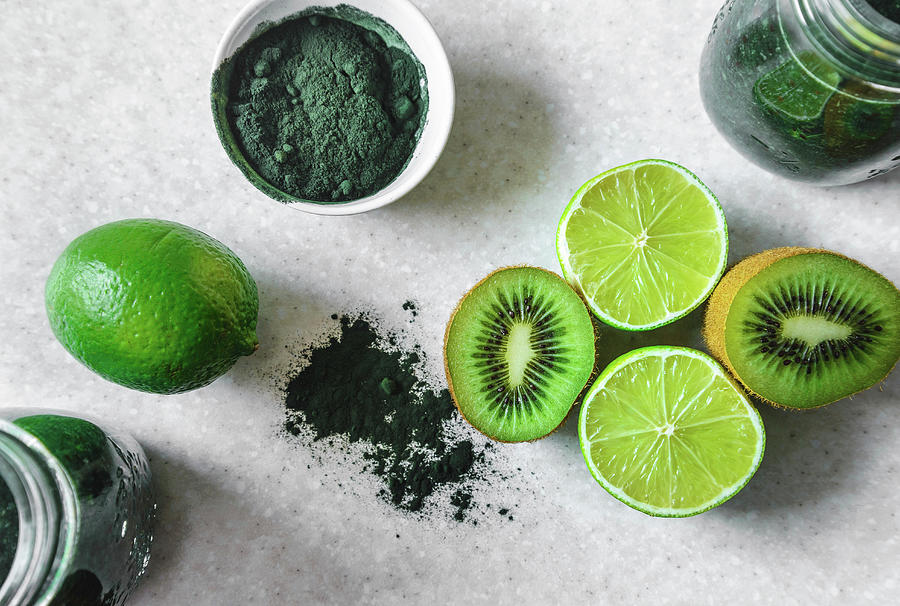 Halved Kiwi And Lime Fruits, Powdered Spirulina, Green Smoothie In Glass Jars Photograph by Albina Bougartchev