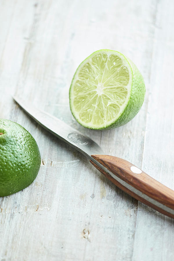 Halved Lime With A Kitchen Knife On A Light Background Photograph by Oliver Brachat
