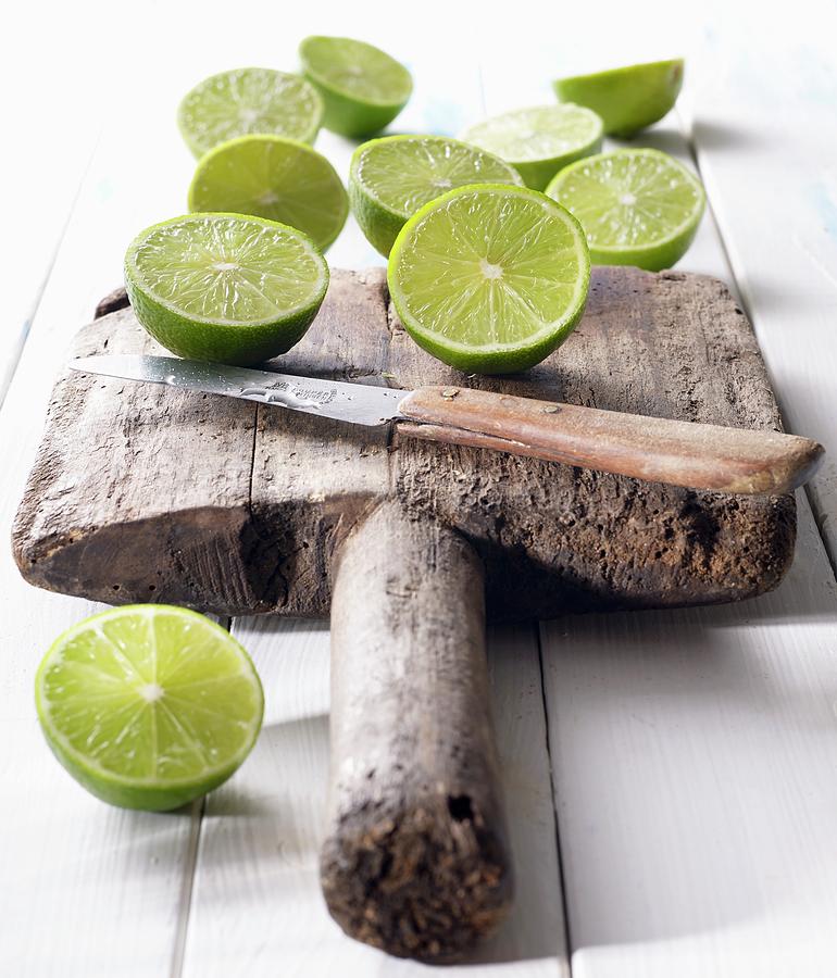 Halved Limes On An Old Wooden Board With A Knife Photograph by Ludger Rose