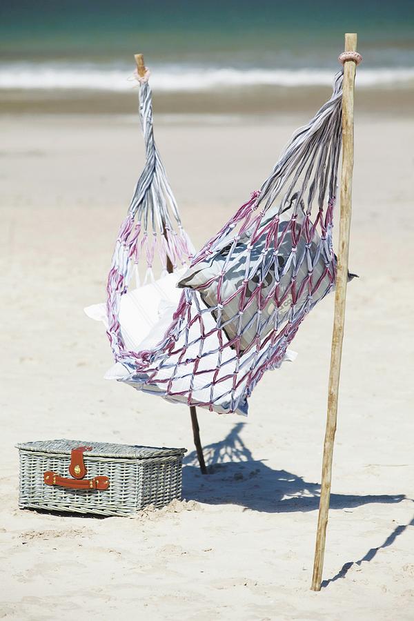 Hammock Attached To Sticks Stuck In Sandy Beach Next To Picnic Basket Photograph by Great Stock!