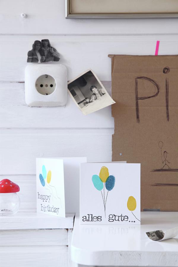 Hand-crafted Birthday Cards With Balloon Motifs Below Black And White Photos On White Wooden Wall Photograph by Thordis Rggeberg