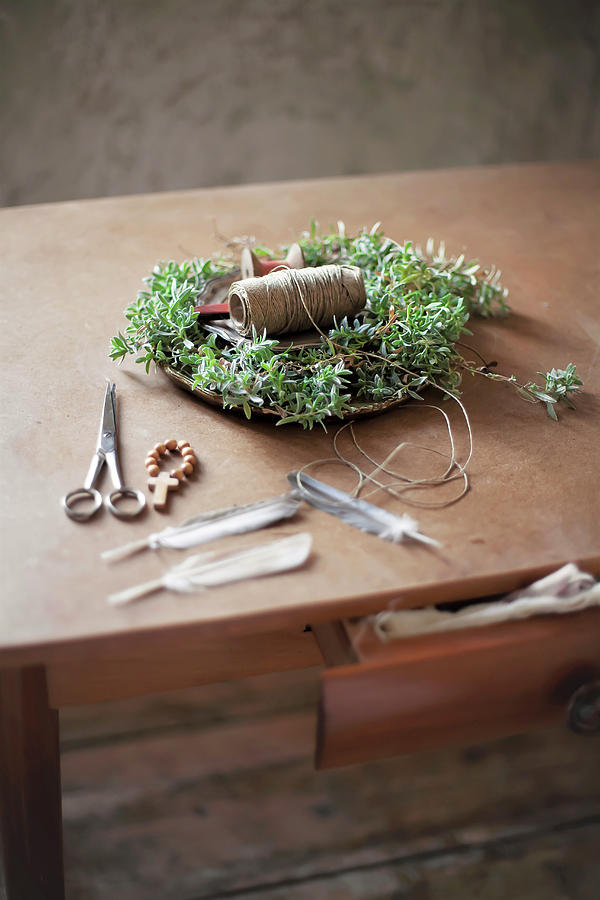 Handmade Chickweed Easter Nest With Twine, Wooden Beads, Scissors And Feathers On Wooden Table Photograph by Alicja Koll