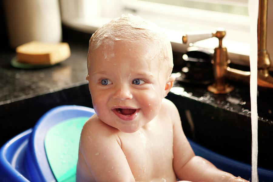 Happy Baby Boy Looking Away While Bathing In Kitchen Sink Photograph by