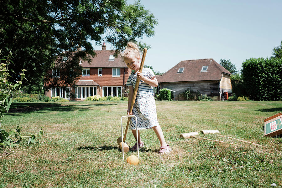 Happy Girl Playing Croquet On Grassy Field At Yard Against Clear Sky During Sunny Day Photograph