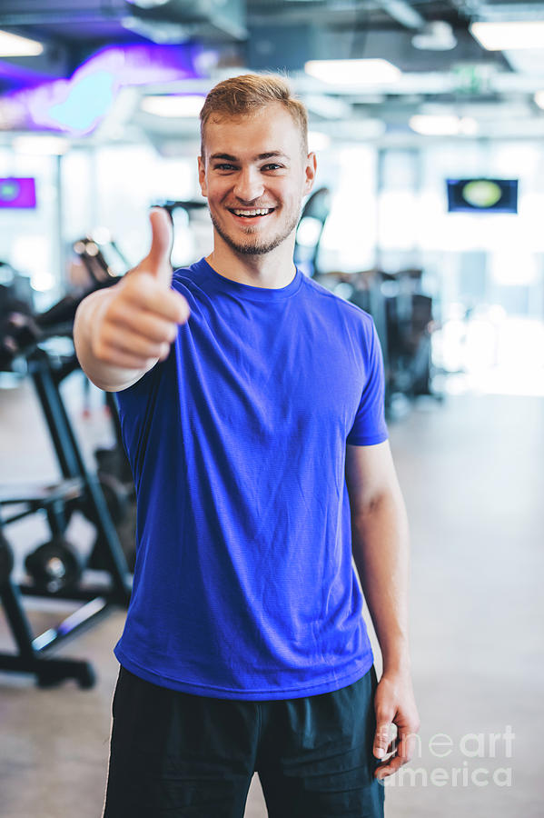 Happy man standing at the gym, showing thumb up. Photograph by Michal Bednarek