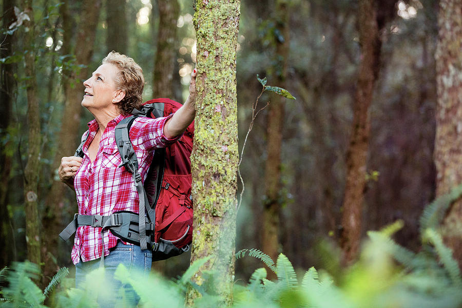 Happy Senior Woman Carrying Backpack Standing Against Trees In Forest ...