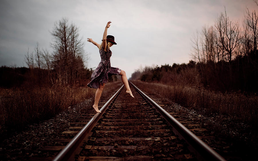 Sunset Photograph - Happy Woman Dancing On Railroad Tracks Against Cloudy Sky During Sunset by Cavan Images