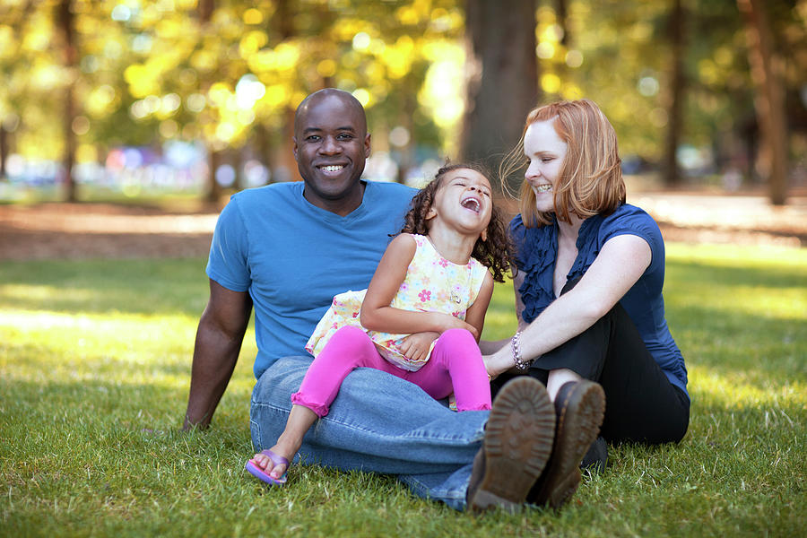 Happy Woman Tickling Daughter Sitting On Man's Lap Photograph By Cavan 